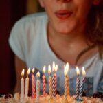 women blowing out birthday cake candles